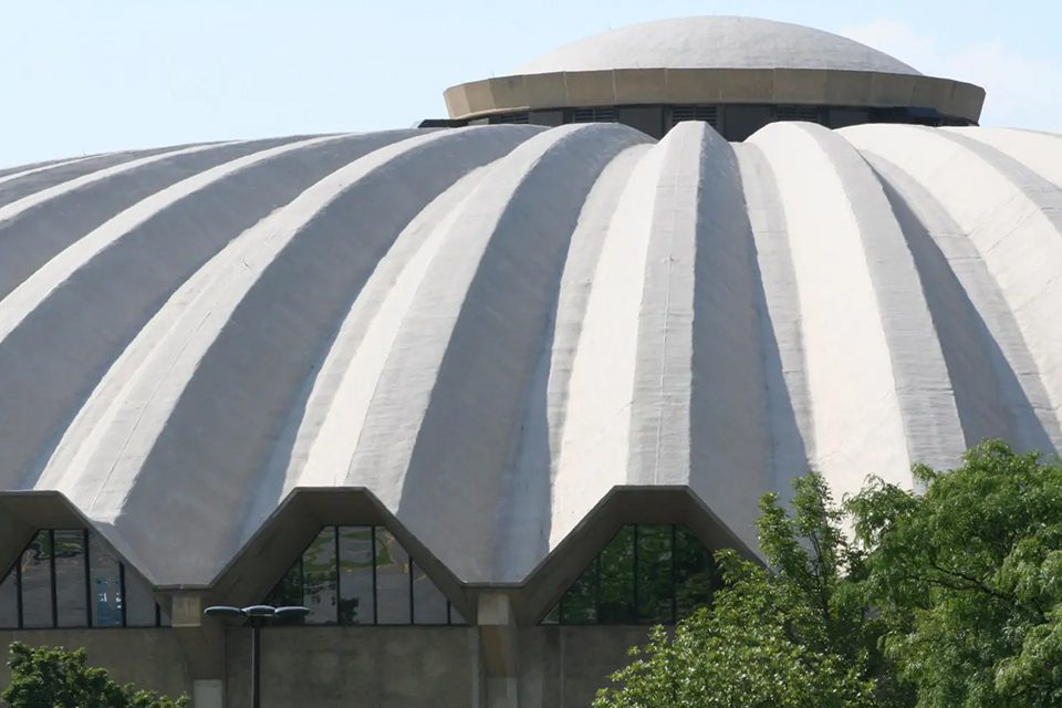 A large building with a dome roof and trees in front of it.