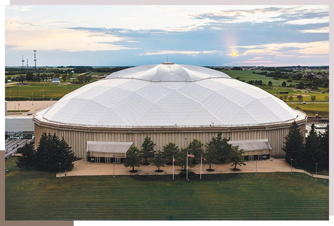 A large white dome shaped building with grass around it.